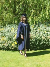 Full length portrait of smiling young woman standing on tree