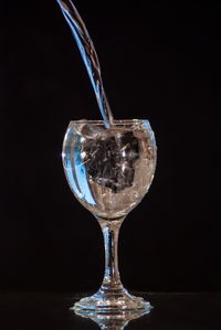 Close-up of wineglass on table against black background