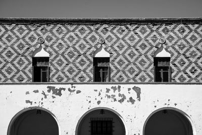 Wooden antique windows with elongated balkons on a painted old wall.