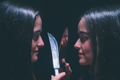 Sisters crossing knife against black background