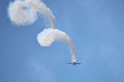 Low angle view of airplane flying against blue sky