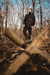 Man standing by bare trees in forest