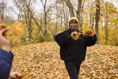 Smiling woman throwing autumn leaves