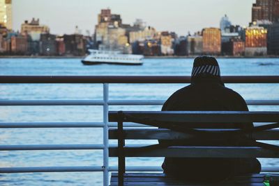 Rear view of man sitting on bench and watching city