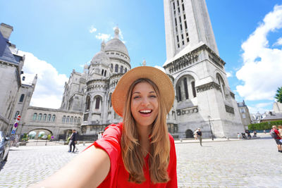 Selfie girl in paris with the basilica of the sacred heart of paris on the background. 