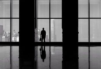 Silhouette man looking at international finance centre through window