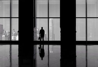 Silhouette man looking at international finance centre through window