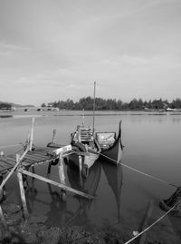 Sailboats moored on lake against sky