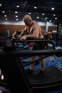 Full length of shirtless man sitting in kitchen