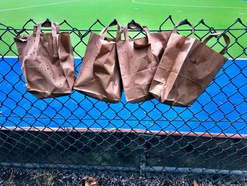 Clothes drying on chainlink fence against sky