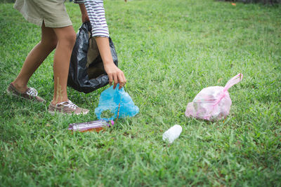 Close-up of woman collecting garbage on grass field