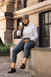 Full length of young woman using mobile phone outdoors