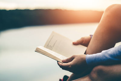 Midsection of person holding book against sea