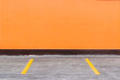 Orange building wall and parking spaces with painted yellow dividers