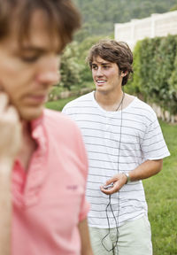 Young man listening to mp3 player with mid adult man in front