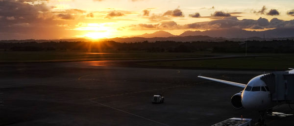 Airplane on runway against sky during sunset