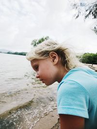 Cute girl looking away while sitting at beach