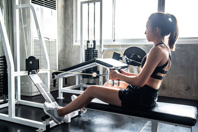 Side view of young woman exercising in gym