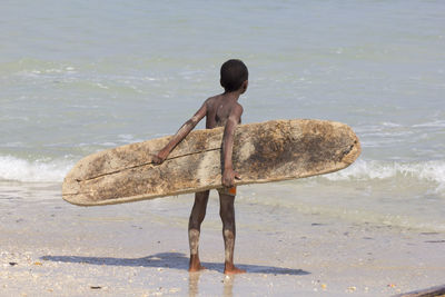 Rear view of shirtless boy on beach