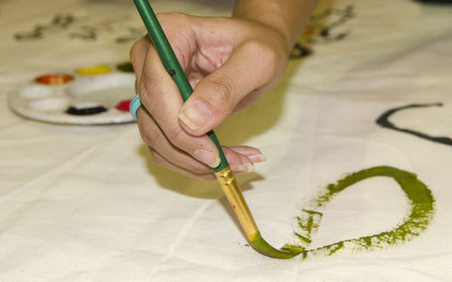 Cropped hand of woman painting on textile