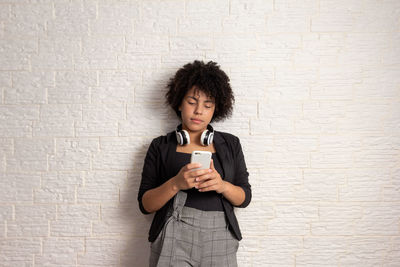 Portrait of young woman standing against wall