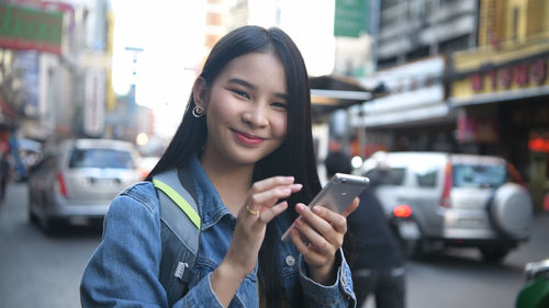 Portrait of young woman using smart phone in city