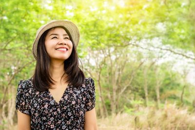 Portrait of smiling young woman standing against plants