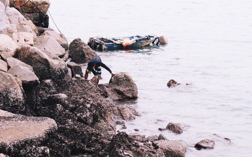 People on rock by sea