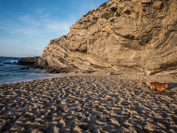 Scenic view of sea by rock formation against sky