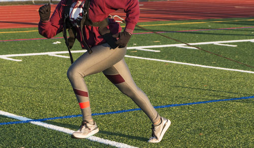 Low section of woman running on soccer field