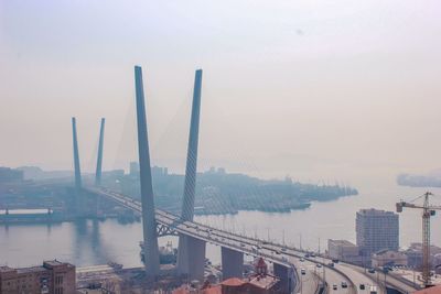 Bridge over river in city against sky