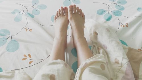 Low section of woman lying on bed