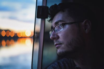 Side view of man against window at sunset