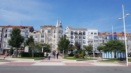 City street by buildings against blue sky