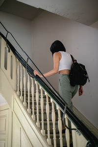 Low angle view of young woman with backpack moving up on steps