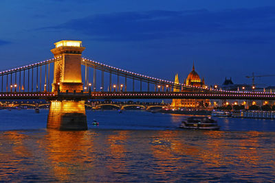 Illuminated bridge over river against sky at night