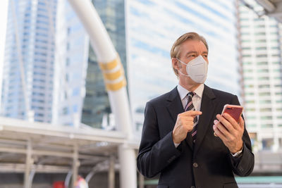Midsection of man holding umbrella standing against built structure