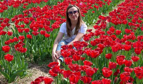 Woman standing by red poppy flowers