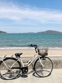 Bicycles on beach by sea against sky