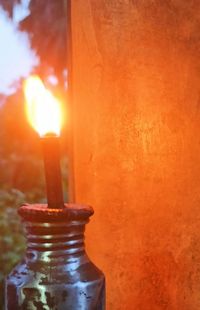 Close-up of illuminated candle against orange wall