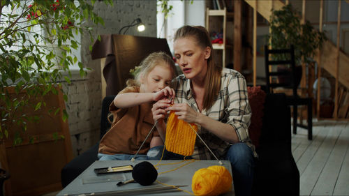 Mother teaching crocheting to daughter