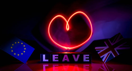 Close-up of illuminated text on red wall at night