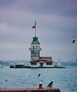 Lighthouse by sea against sky