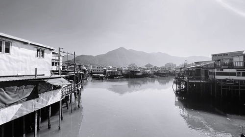 Sailboats moored at harbor by buildings against sky