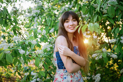 Portrait of smiling young woman standing against plants