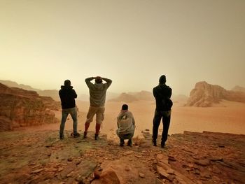 Rear view of people standing on shore against sky