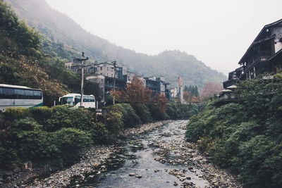 Road amidst trees and mountains against clear sky