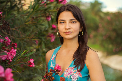 Portrait of beautiful young woman standing by plants in park