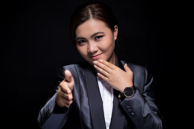 Portrait of a smiling young woman against black background