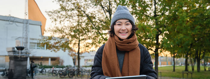 Portrait of smiling young woman standing in park